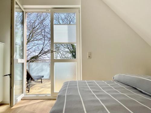 a bedroom with a bed and a sliding glass door at Am Dahmer Leuchtturm 23f in Dahme