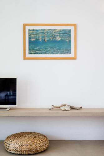 a white wall with a shelf with a picture and a stool at Ondalina in Kardiani