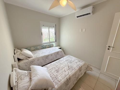 ein Schlafzimmer mit zwei Betten und einem Fenster in der Unterkunft Cobertura com Piscina Privativa e Vista Mar in Riviera de São Lourenço