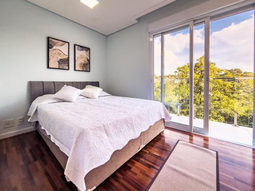 ein Schlafzimmer mit einem Bett und einem großen Fenster in der Unterkunft Luxo e segurança - 30 minutos de SP in Carapicuíba