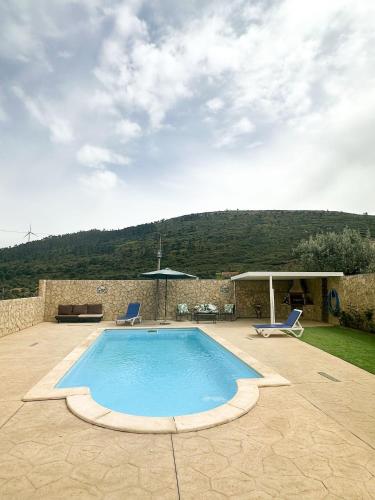 a swimming pool with two chairs and an umbrella at Refúgio da Serra in Porto de Mós