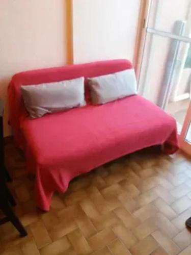 - un canapé rouge avec deux oreillers dans l'établissement Maison à Marseillan près de la plage avec terrasse, à Marseillan