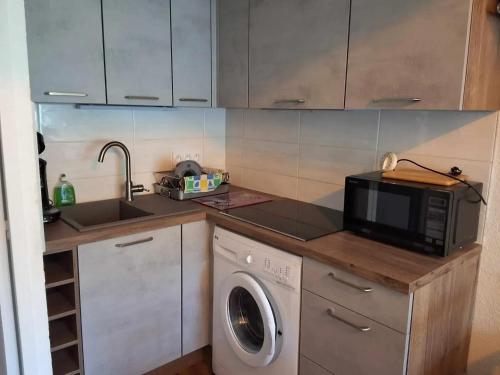 une cuisine avec un lave-linge et un micro-ondes dans l'établissement Maison à Marseillan près de la plage avec terrasse, à Marseillan