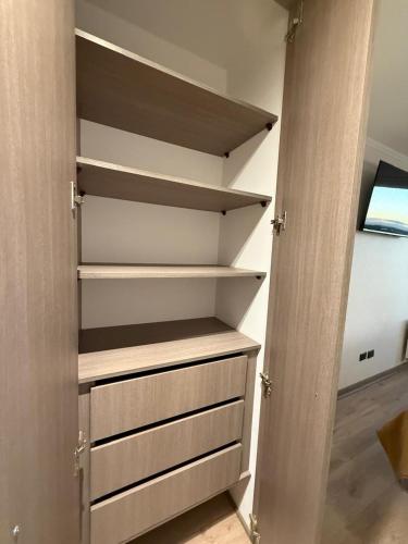a closet with wooden shelves and a door at Céntrico,acogedor, con gran vista y estacionamiento in Concepción