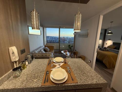 a kitchen with a table with plates on top of it at Céntrico,acogedor, con gran vista y estacionamiento in Concepción