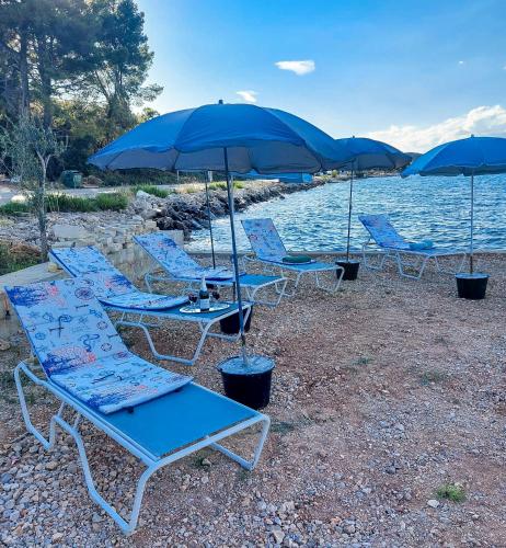 a group of chairs and umbrellas on a beach at Apartman Drače in Drače