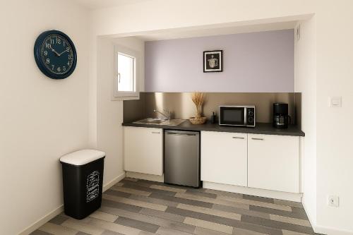 une cuisine avec des placards blancs et une horloge murale dans l'établissement Appart du cirque centre historique, à Troyes