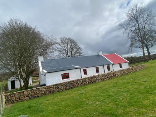 a white barn with a stone wall in a field at Farm Stay at THE GLEBE COTTAGE KILREA in Tamlaght