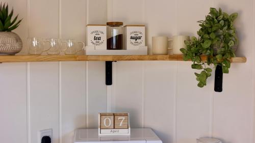 a shelf with a clock and glasses on it at The Gatwick Cabin With Airport Parking Available in Horley