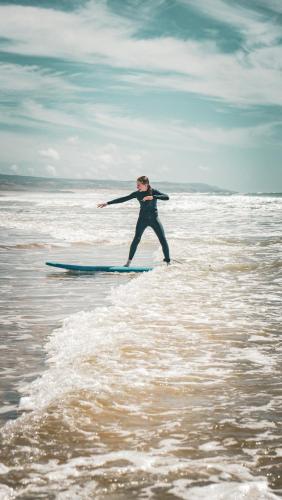a person standing on a surfboard in the ocean at IBI Surf House in Sidi Kaouki