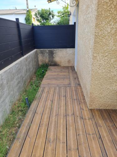 une passerelle en bois à côté d'un bâtiment avec une clôture dans l'établissement Appartement L'almannare, à Hyères