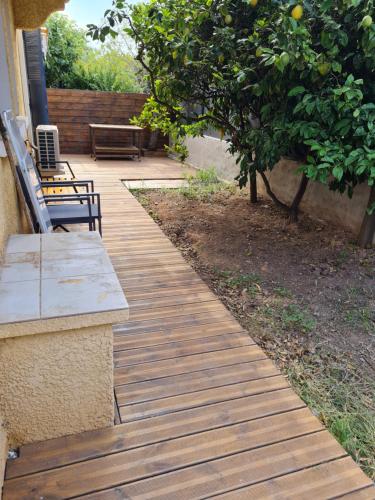 une passerelle en bois avec deux bancs et un pommier dans l'établissement Appartement L'almannare, à Hyères