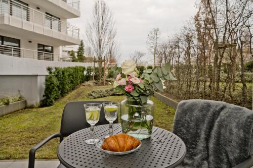 a table with a vase of flowers and wine glasses at BlueApart Apartamenty Na Klifie in Władysławowo