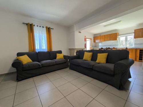 a living room with two black couches and yellow pillows at Fonte da Rosa Guest House APT1 in Belmonte
