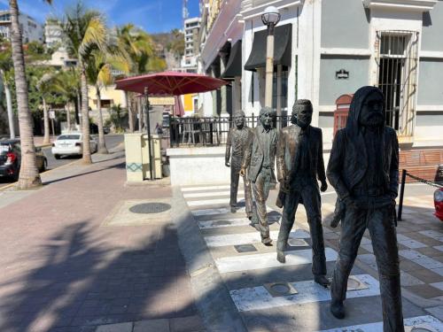 a statue of three men standing on a street at Hotel La Siesta Malecón in Mazatlán