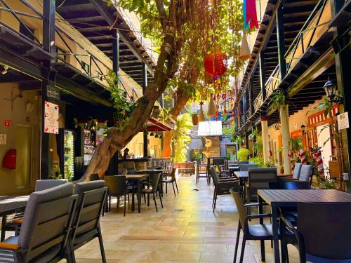 an empty restaurant with tables and chairs and a tree at Hotel La Siesta Malecón in Mazatlán
