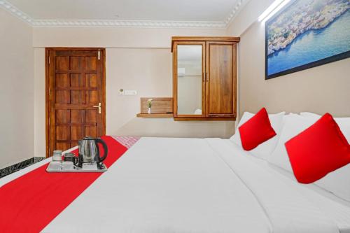 a bedroom with a large white bed with red pillows at Hotel O Poptavern Premium in Trivandrum