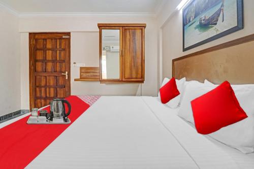a bedroom with a large white bed with red pillows at Hotel O Poptavern Premium in Trivandrum