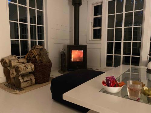 a living room with a fireplace with a table and a stove at Villa Betula Nature Gem At Hårbølle Harbor in Askeby