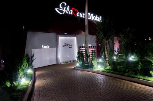 a night view of a building with a neon sign at Motel Glamour in Maringá