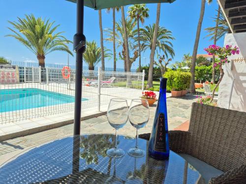 zwei Weingläser auf einem Tisch neben einem Pool in der Unterkunft 8i Ocean Front Playa 4 in San Bartolomé de Tirajana