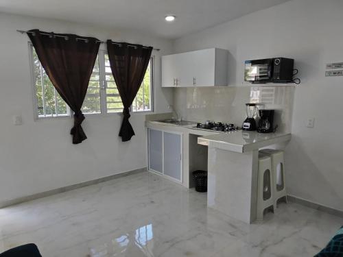 cocina blanca con encimera y microondas en Casa los Sauces, en Tepic