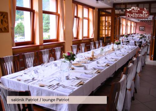 a long table in a restaurant with white tables and chairs at Hotel Podhradie in Považská Bystrica