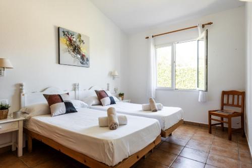 two beds in a room with a window at Villa Miguel in Cala en Bosc