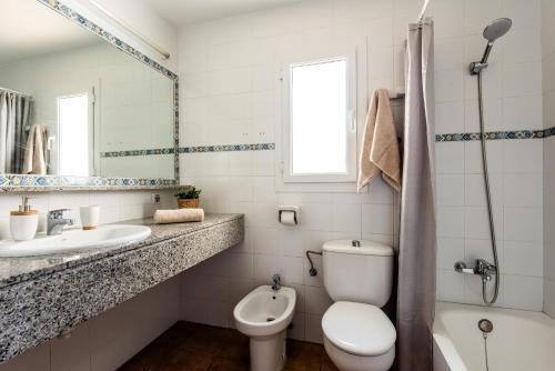 a white bathroom with a toilet and a sink at Villa Miguel in Cala en Bosc