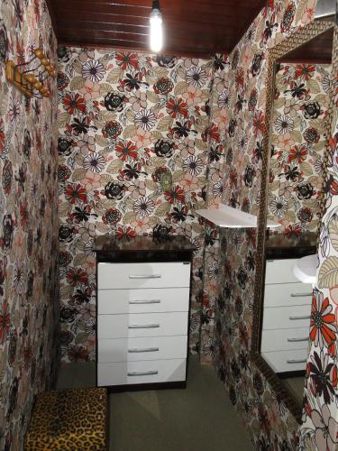 a bathroom with a floral wallpaper and a mirror at Pousada das Acerolas in Penedo