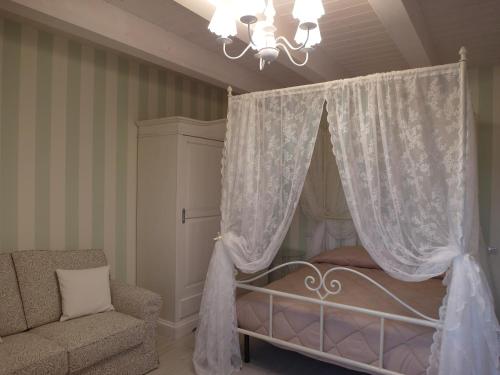 a bedroom with a canopy bed with a chair and a chandelier at Ca' Del Conte in Padula