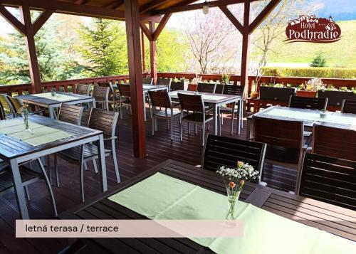a restaurant with tables and chairs on a deck at Hotel Podhradie in Považská Bystrica