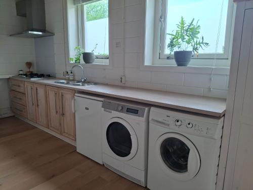 a kitchen with a washing machine and a sink at Huisje Suus, inclusief jacuzzi, kano en kajak in Zuid-Scharwoude