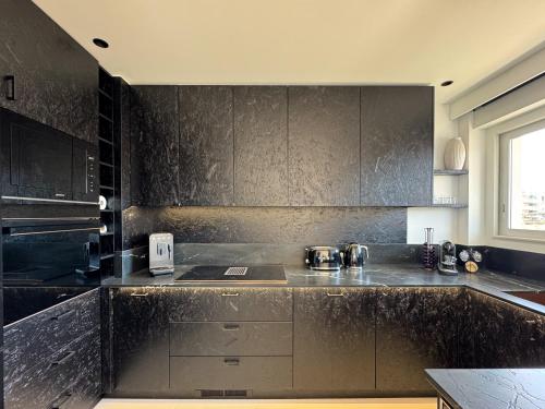 une cuisine avec un plan de travail noir avec un évier dans l'établissement Cavalaire plein centre, Appartement design 70m2 à 2mn de la plage - Garage privé -Terrasse, à Cavalaire-sur-Mer