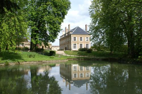 a large building with a reflection in a river at B&B Vassy Etaule in Avallon