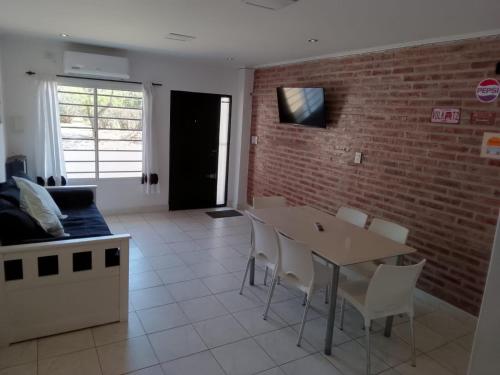 ein Wohnzimmer mit einer Ziegelwand, einem Tisch und Stühlen in der Unterkunft Alquiler por día General Villegas in General Villegas