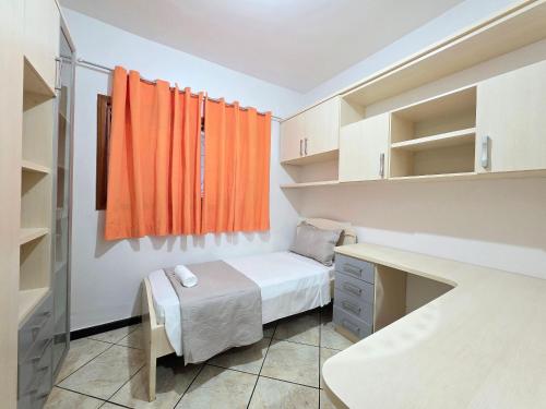 una piccola camera con tenda arancione e letto di Casa Quintal Amplo prox Cataratas 4 quartos a Foz do Iguaçu