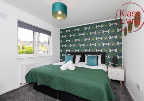 a bedroom with a large bed with a green blanket at Aitkenhead house by Klass Living in Coatbridge