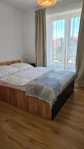 a bed in a bedroom with a large window at Apartamenty Rynek 3 Niebieski in Osie