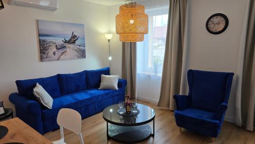a living room with a blue couch and two chairs and a table at Apartamenty Rynek 3 Niebieski in Osie