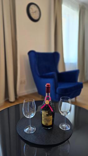 a bottle of wine and two wine glasses on a table at Apartamenty Rynek 3 Niebieski in Osie