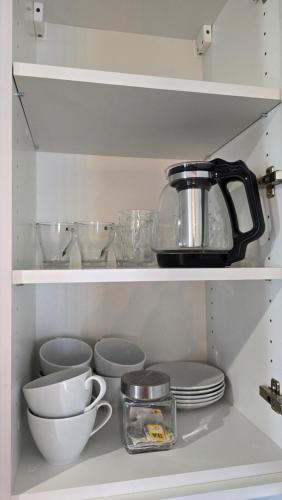 a kitchen shelf with dishes and a tea kettle at Apartamenty Rynek 3 Niebieski in Osie