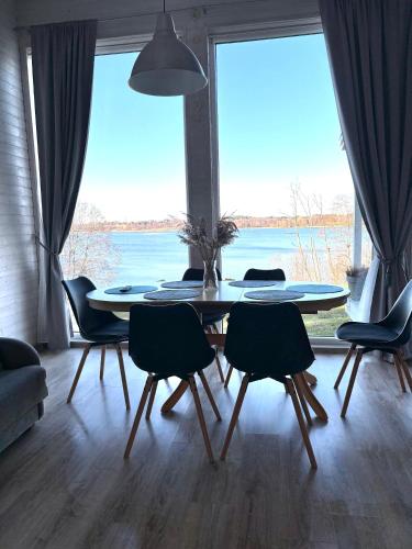 a dining room with a table and chairs and a large window at Sodyba Po klevu in Molėtai