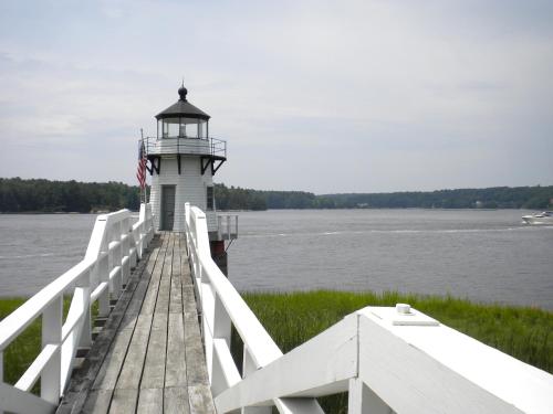 a lighthouse on a dock with a flag on it at Benjamin F. Packard House Bed and Breakfast in Bath