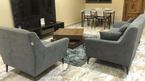a living room with couches and a television and a table at Norichyank Apartments in Amasaman