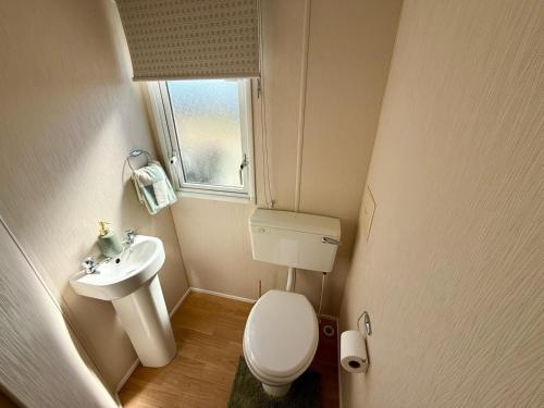 a small bathroom with a toilet and a sink at Poppys Place in Ingoldmells