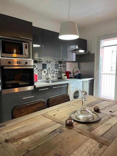 une cuisine avec une table en bois et des chaises ainsi qu'une cuisine avec une cuisinière dans l'établissement Appartement T3 centre ville Propriano, à Propriano