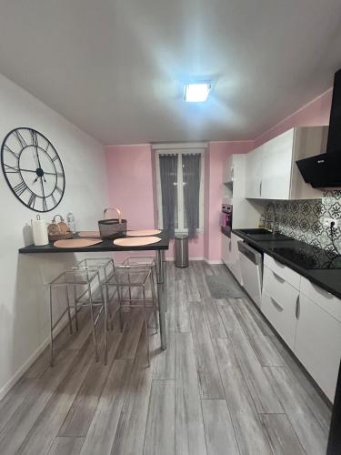 une cuisine avec une table et une horloge au mur dans l'établissement Jolie maison de ville, à Montluçon