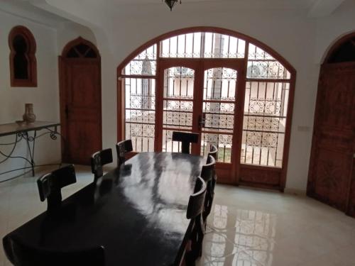 a dining room with a table and chairs and a large window at DAR SALIA entre Agadir et Taghazout in Aourir