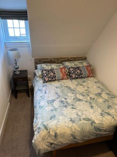 a bedroom with a bed and a lamp and a window at Eilean View in Lamlash